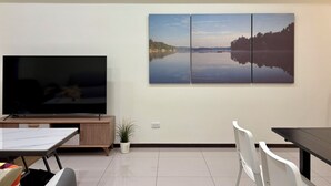 A modern living room with a large flat-screen TV, a dining table, and a seating area.