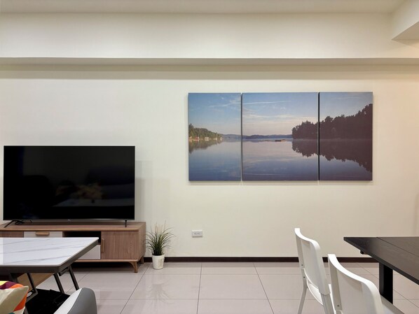 Una sala de estar moderna con un televisor de pantalla plana grande, una mesa de comedor y un espacio para sentarse.