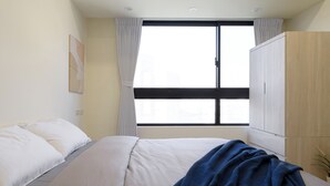 A bedroom with a bed, a window, and a wardrobe.