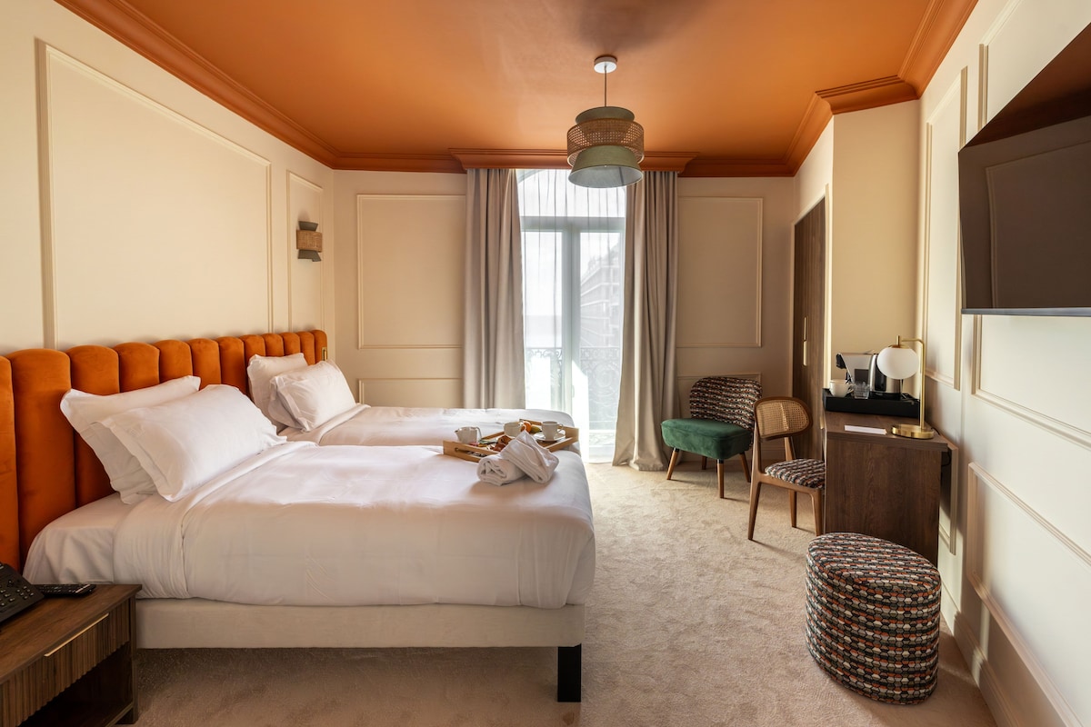 A hotel room with a large bed, a desk, a chair, and a television.