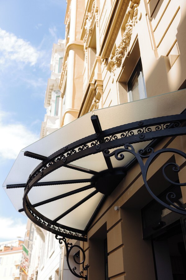 A building with ornate architectural details, including a decorative awning with intricate metalwork. - HOTEL AMBASSADOR NICE (Nice)