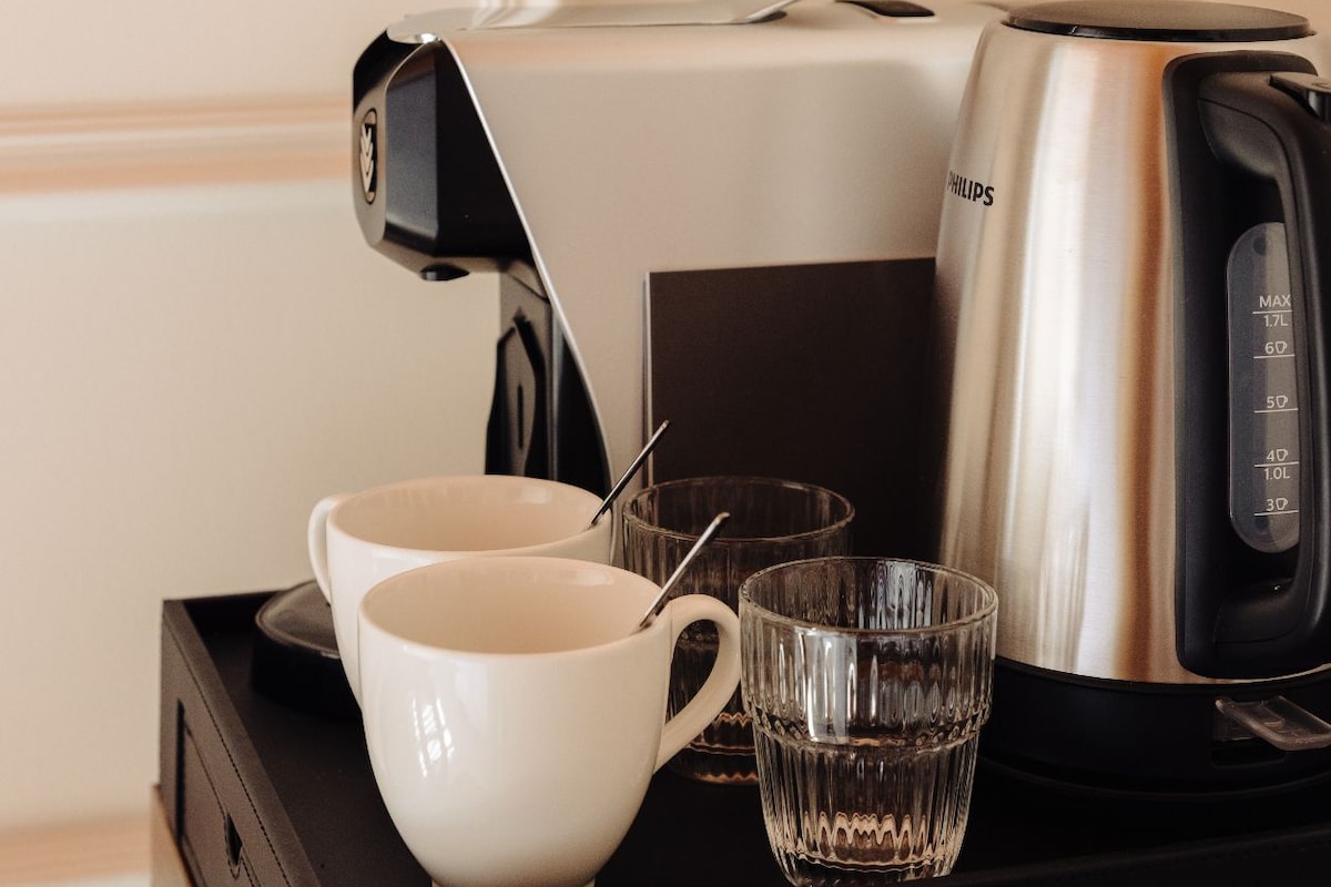 Une machine à café, une tasse blanche et un verre sur un plateau noir.