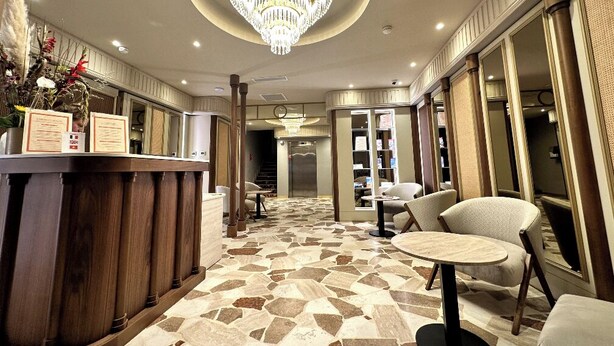 En hotellobby med en receptionsdisk, en sittgrupp och en kristallkrona.