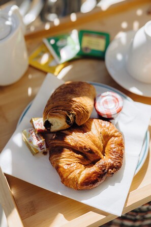 A croissant on a plate with a napkin, a jar of jam, and a packet of butter. - HOTEL AMBASSADOR NICE (Nice)