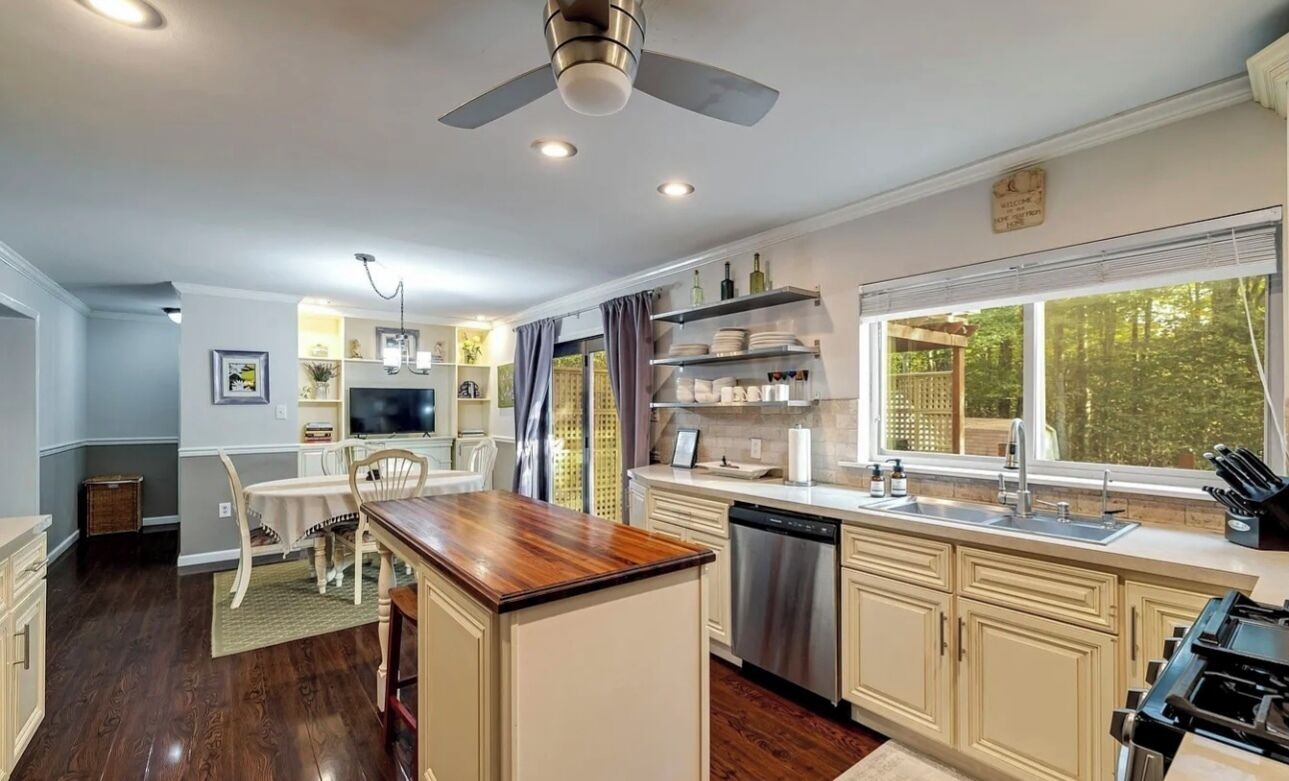 A modern kitchen with a central island, built-in appliances, and a large window offering a view of the outdoors.