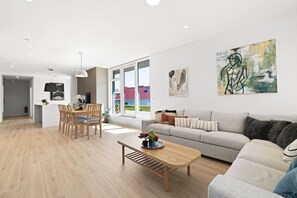 Uma sala de estar moderna com sofá, mesa de centro e área de jantar.