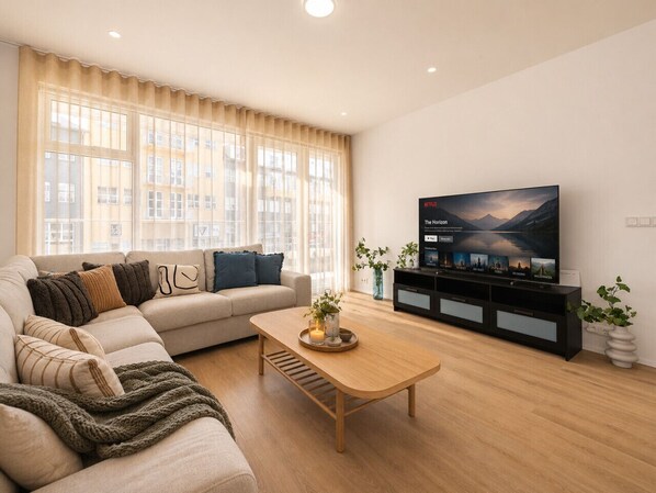 Ein Wohnzimmer mit einer Couch, einem Couchtisch, einem Fernseher und einer Pflanze.