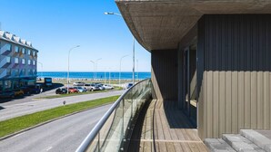 Ein modernes Gebäude mit einem Balkon mit Blick auf einen Strand und einen Parkplatz.