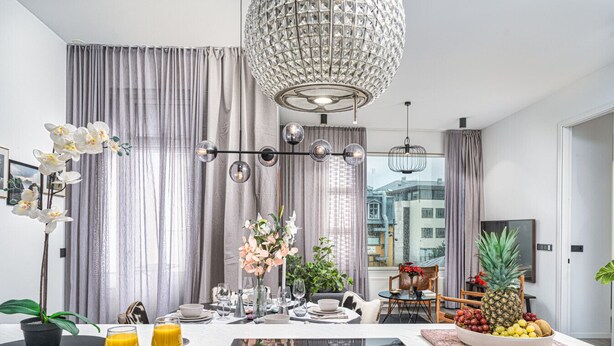 A modern dining area with a chandelier, dining table set for four, and a view of the city through large windows. - Vibrant City Center Escape (Reykjavík)