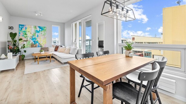 Un apartamento moderno con comedor, sala de estar y ventanas amplias que ofrecen vista a la ciudad.