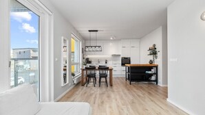 Un apartamento moderno con comedor, cocina y un ventanal grande con vistas a la calle.