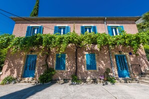 Un bâtiment doté de nombreuses fenêtres et portes, dont certaines sont recouvertes de lierre.