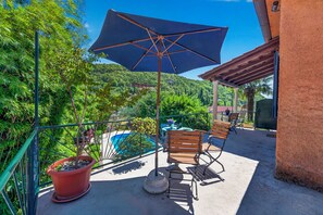 Un balcon avec une piscine, des chaises, une table et un pot de fleurs.