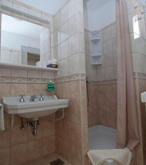 A bathroom with a sink, mirror, and shower.