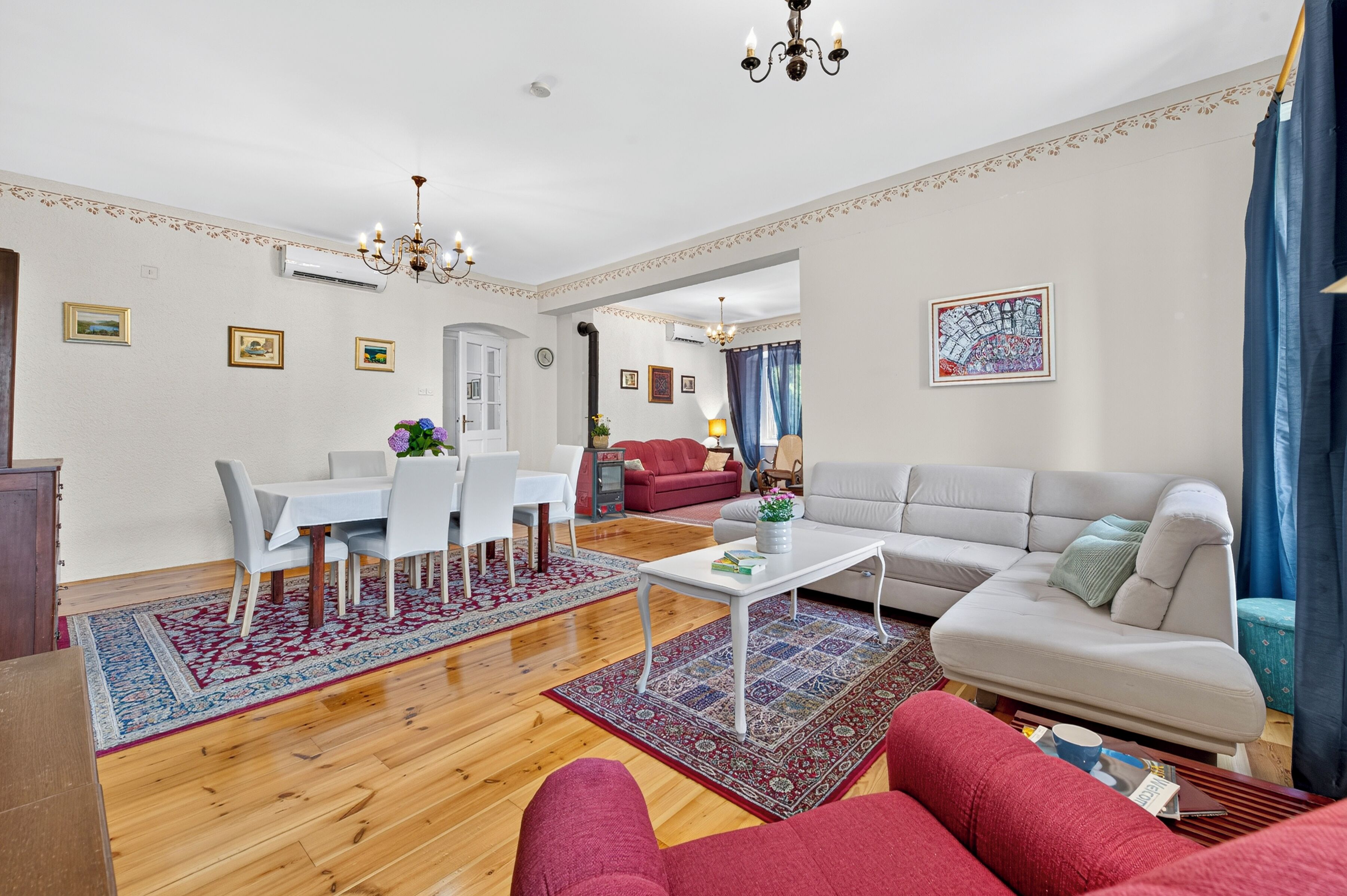 A spacious living area with a dining table, sofa, and a decorative rug.