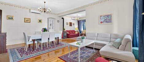 A spacious living area with a dining table, sofa, and a decorative rug.