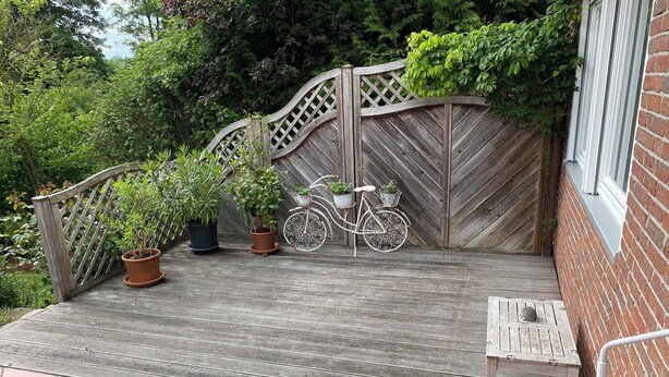 A wooden deck with potted plants and a decorative bicycle.