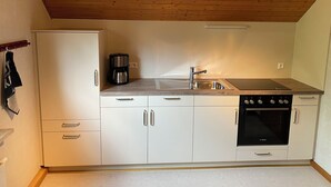A compact kitchen with white cabinets, a Bosch oven, a sink, and a coffee maker.