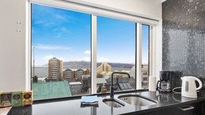 Eine moderne Küche mit einem großen Fenster, einer Kaffeemaschine und einem Wasserkocher auf der Arbeitsfläche.