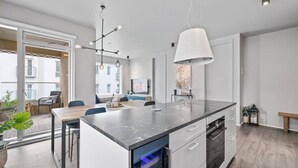 A modern kitchen with a large island, built-in appliances, and a dining area with a view. - Stunning City Center Oasis. (Reykjavík)