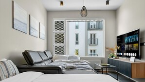 A modern hotel room with a bed, a desk, a television, and a window with a view of the city. - Stunning City Center Oasis. (Reykjavík)