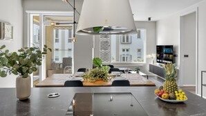A modern dining area with a large table, pendant lighting, and a view of the city through large windows. - Stunning City Center Oasis. (Reykjavík)