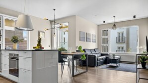 A modern kitchen with a central island, a dining area with a black sofa, and a living room with a black leather couch. - Stunning City Center Oasis. (Reykjavík)