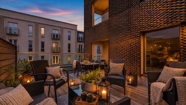 A modern outdoor patio with wicker furniture, a dining table, and potted plants. - Stunning City Center Oasis. (Reykjavík)