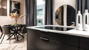 Une cuisine moderne dotée d’un îlot central, de meubles de rangement aux couleurs sombres et d’un coin repas avec une table ronde et des chaises.