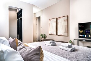 Ein Hotelzimmer mit Bett, Fernseher, Kleiderschrank und einer Tür zu einem anderen Raum.