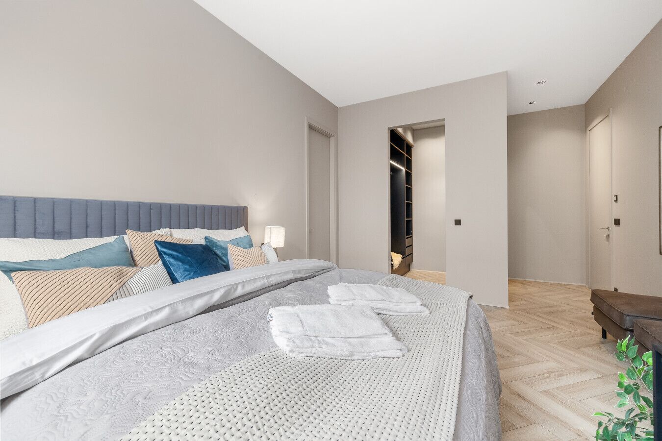 A modern bedroom with a large bed, a headboard, and a walk-in closet.
