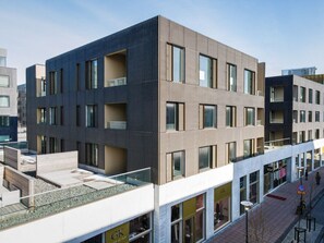 Ein modernes, mehrstöckiges Gebäude mit flachem Dach, großen Fenstern und einer Fassade aus Ziegel und Beton.