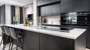 Une cuisine moderne avec des meubles de couleur bois foncé, un plan de travail en marbre et un four encastré.