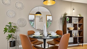 A dining area with a round table, brown chairs, a large mirror, and a modern light fixture. - Prime Location Gem in the Heart of Reykjavík (Reykjavík)