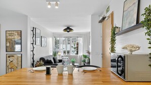 A modern kitchen with a wooden countertop, white cabinets, and a dining area with a table set for two. - Prime Location Gem in the Heart of Reykjavík (Reykjavík)