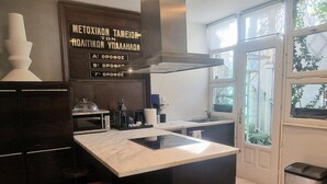 A modern kitchen with a central island, wooden flooring, and a view through a glass door. - Comfy penthouse in the center of Athens (Athina)