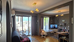 A spacious living area with a large sofa, a patterned rug, and a television. - Comfy penthouse in the center of Athens (Athina)
