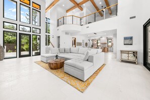 A spacious living room with a large sectional sofa, a wooden coffee table, and a yellow patterned rug.