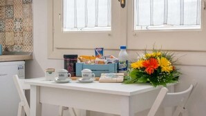 Ein weißer Tisch mit einer blauen Schachtel, einer Flasche, einer Kaffeetasse und einer Blumenkomposition.