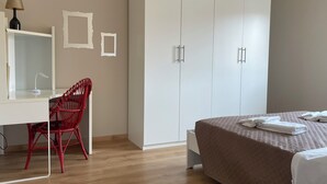 Un dormitorio con cama, escritorio, silla, armario y lámpara.