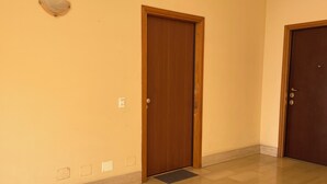 Un pasillo con dos puertas de madera, un interruptor de luz y una lámpara fijada a la pared.