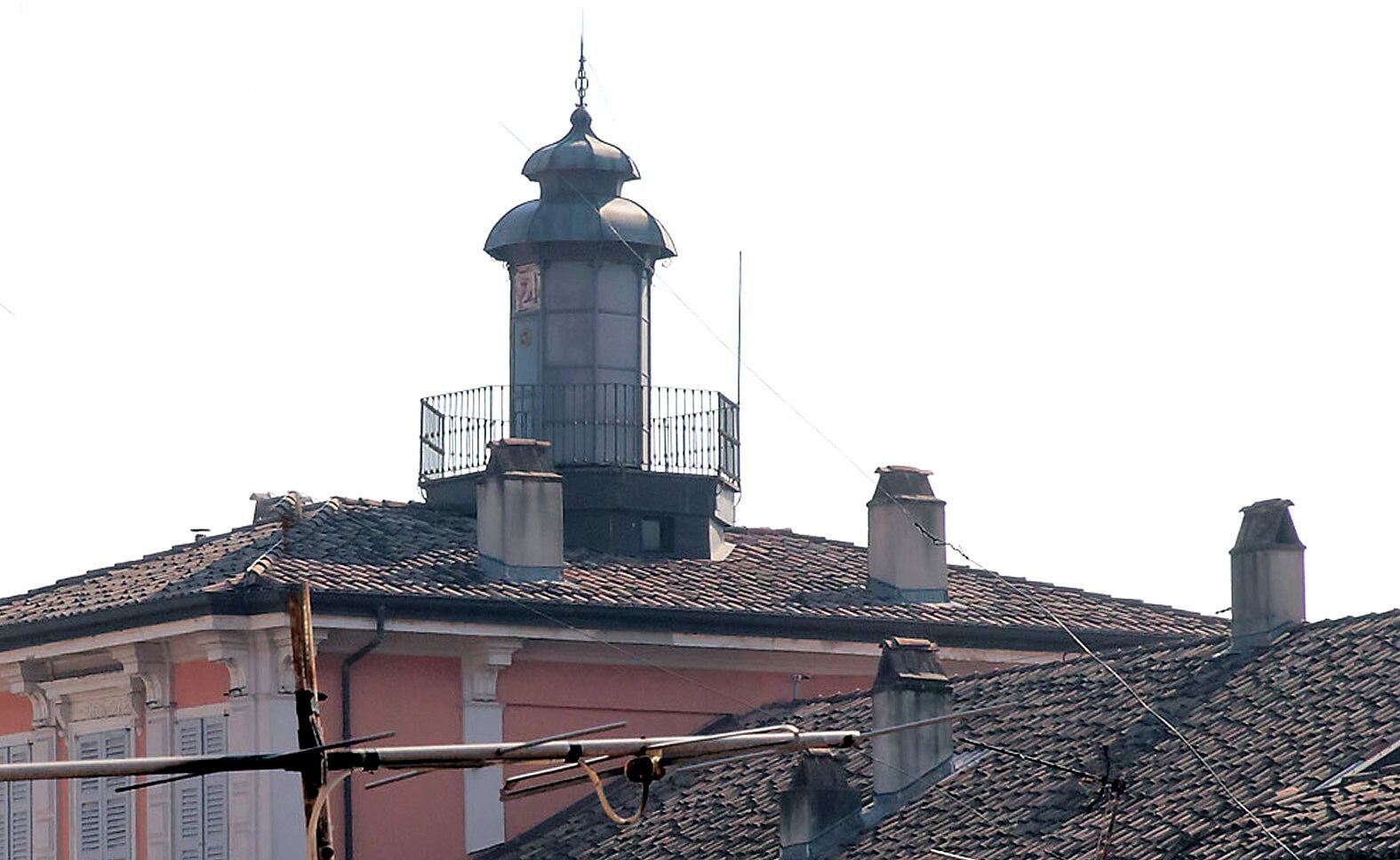 A building with a prominent tower, a balcony, and a tiled roof.