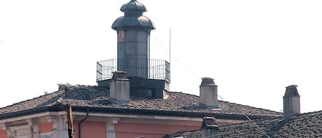 A building with a prominent tower, a balcony, and a tiled roof.