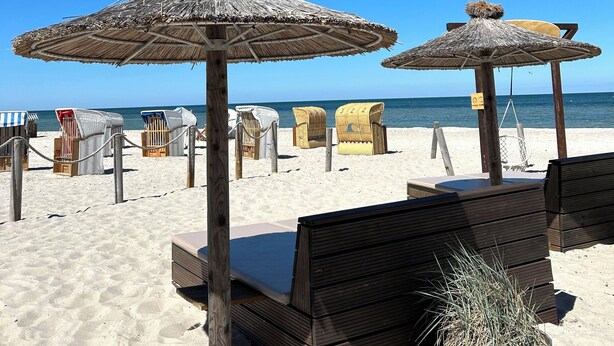 A beach with wooden lounge chairs and thatched umbrellas, a sandy beach, and a clear blue sky. - Lines to Huus Vacation Home – Near the Baltic Sea Beach (Neukirchen)