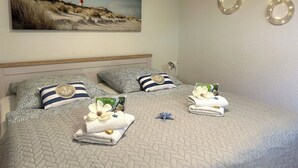 A neatly made bed with striped pillows, a lighthouse painting on the wall, and two circular wall decorations. - Lines to Huus Vacation Home – Near the Baltic Sea Beach (Neukirchen)