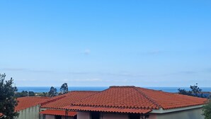 A building with a red-tiled roof and a view of the ocean.