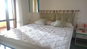 A bed with a quilted white duvet, striped pillows, and a headboard with hanging decorations.