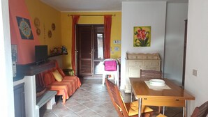 A compact living space with a sofa, a dining table, and a kitchen area.