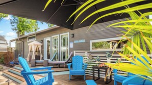 Une terrasse avec des chaises Adirondack bleues, une table de billard et un panneau indiquant « SERVIETTES POUR LA PISCINE ».