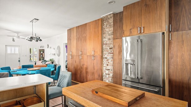 Une cuisine moderne avec des meubles en bois, un grand réfrigérateur en acier inoxydable et un plan de travail en bois.